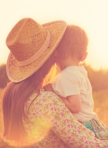 A mom holding her little one close in warm golden light