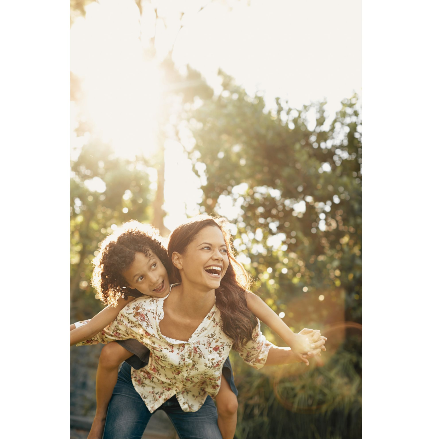 A laughing mom giving her daughter a piggyback ride outdoors in warm golden sunlight